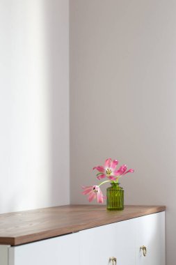 Beyaz arka planda cam yeşil vazoda pembe laleler