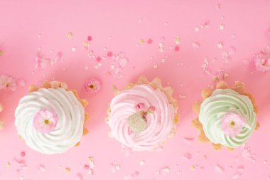 Pembe arka planda bahar çiçekleri olan pembe ve yeşil kekler.