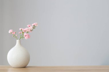 Ahşap masadaki seramik vazoda pembe güller