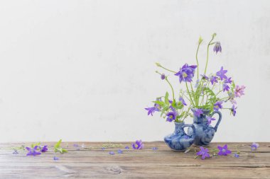 Eski ahşap masada mavi sürahi içinde yaz çiçekleri