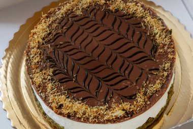 Beyaz bir karton kutuda çikolatalı şam fıstıklı kek.