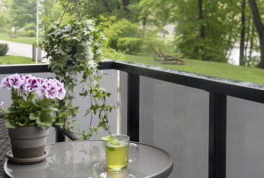 Yağmurda balkonda bir fincan yeşil çay