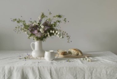 Seramik sürahi süt ve ekmek içinde çiçeklerle dolu beyaz bir hayat.