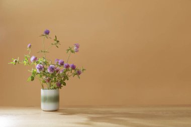 Seramik bardakta yoncalarla dolu tahta masada.