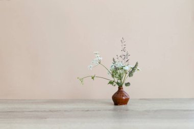 Seramik vazodaki kır çiçekleriyle dolu ahşap masa üzerinde hayat