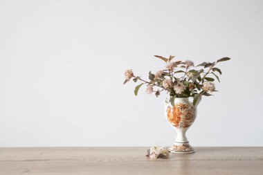 spirea çiçekleri arka plandaki eski seramik vazoda beyaz duvarda