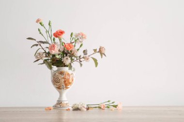 Arka plandaki beyaz duvarda eski seramik vazoda yaz çiçekleri