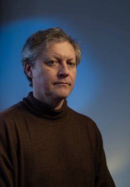 Mavi arka planda orta yaşlı bir adamın portresi.