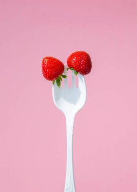 Büyük plastik bir çatalda kırmızı olgun çilekler.