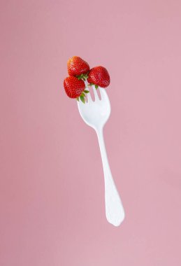 Büyük plastik bir çatalda kırmızı olgun çilekler.