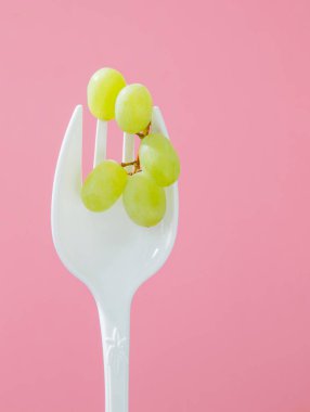 Pembe arka planda büyük beyaz çatallı yeşil üzümler