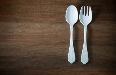 Büyük plastik çatal ve kaşık koyu ahşap masada.