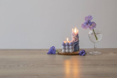 Ahşap masada yanan mumlarla mavi gözler.