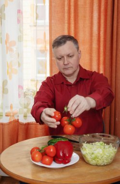 Bir adam mutfağında sebze salatası hazırlar.