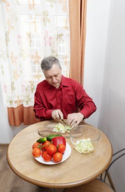 Bir adam mutfağında sebze salatası hazırlar.