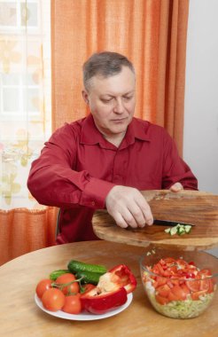 Bir adam mutfağında sebze salatası hazırlar.
