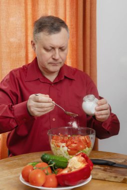 Bir adam mutfağında sebze salatası hazırlar.