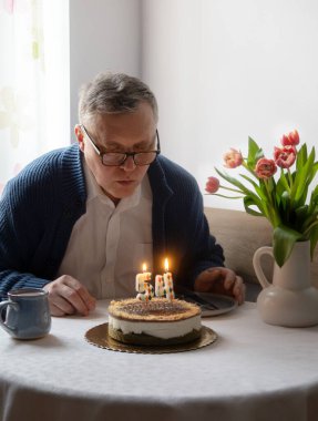 Adam doğum günü pastasında mumları üflüyor mutfakta tek başına.
