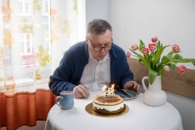 Adam doğum günü pastasında mumları üflüyor mutfakta tek başına.