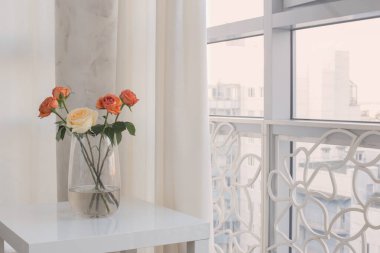 Vazodaki güller penceredeki beyaz masada.