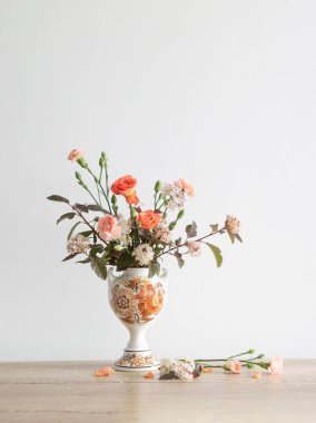 Arka plandaki beyaz duvarda eski seramik vazoda yaz çiçekleri