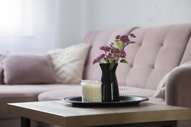 Oturma odasında pembe çiçekler tepside siyah vazoda.