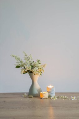 Vazoda beyaz leylak çiçekleri ve yanan mumlar.