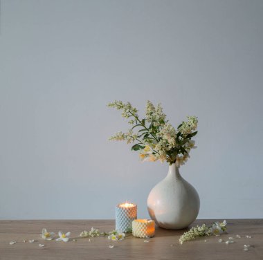 Vazoda beyaz leylak çiçekleri ve yanan mumlar.