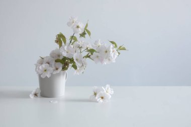 Beyaz masadaki seramik vazoda bahar çiçekleri