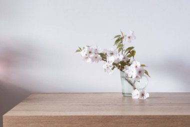 Tahta masada cam bardakta bahar çiçekleri.