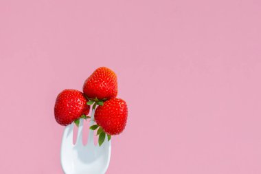 Büyük plastik bir çatalda kırmızı olgun çilekler.