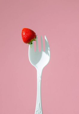 Büyük plastik bir çatalda kırmızı olgun çilekler.