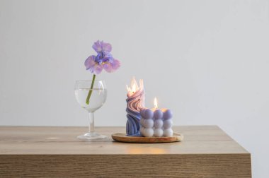 Ahşap masada yanan mumlarla mavi gözler.