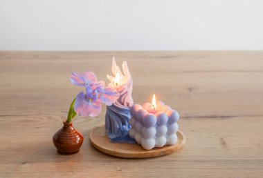 Ahşap masada yanan mumlarla mavi gözler.