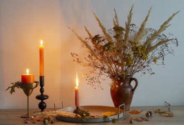 Arka planda yanan mumlarla dolu sonbahar buketi.