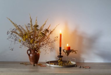 Arka planda yanan mumlarla dolu sonbahar buketi.