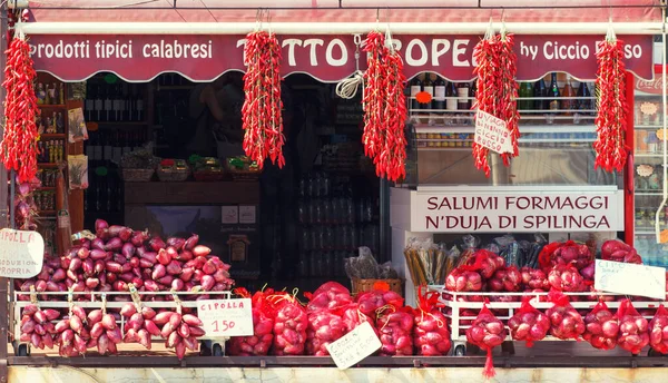 典型的用卡拉布里亚农民产品的食品店 特罗帕的红洋葱热辣椒陈列柜上的酒瓶 图库图片