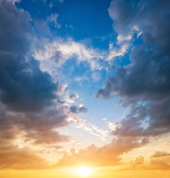 Vibrant sunset sky with yellow sunlight and clouds at blue sky