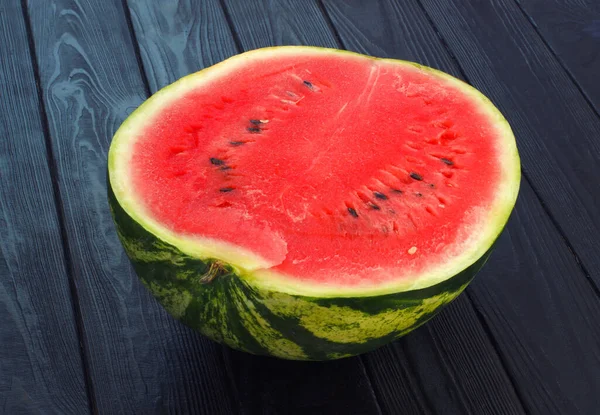 Die Hälfte Der Wassermelone Auf Schwarzem Holzgrund Scheiben Schneiden Rotes lizenzfreie Stockfotos