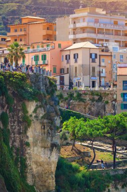 Turistler dağ balkonunda görüş açısına sahipler. Eski Tropea şehrinin binalarıyla dolu bir dağ duvarı. Deniz kenarındaki Calabria kasabasının renkli mimarisi. 