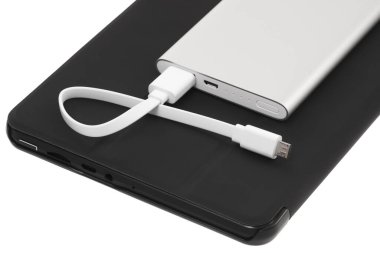 Beyaz arkaplanda harici güç bankası şarjı ve kablosu olan tablet pc.
