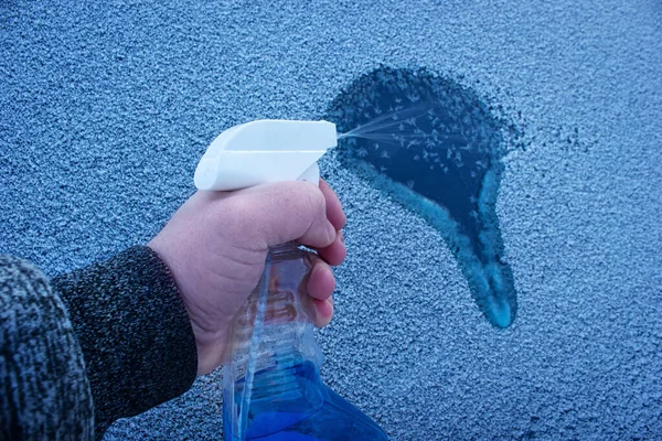 从汽车挡风玻璃上取下冰块 冬季与液体喷雾一起进行车窗除霜 — 图库照片