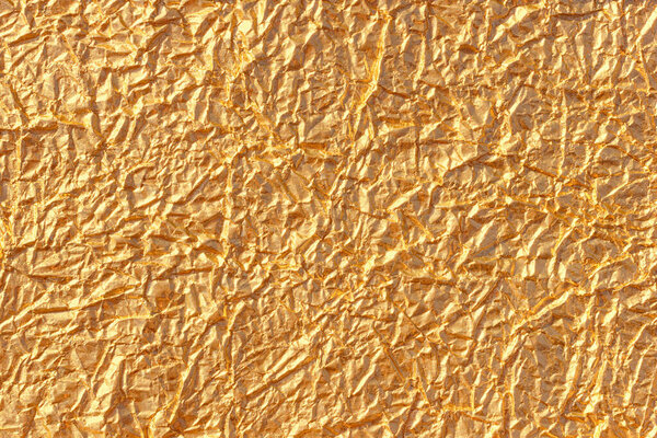 Golden foil background. Abstract wrinkled texture pattern. Metallic wrap paper texture or backdrop.