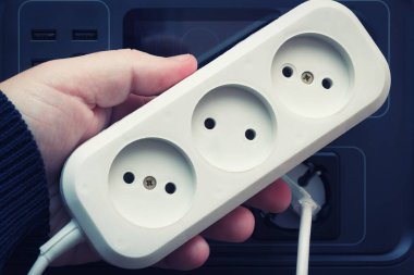 Priz için elektrik uzatma tişörtü. Şarj istasyonuyla elektrik kesintisi. Elektrikli ev aletleri, seçici odaklanma.