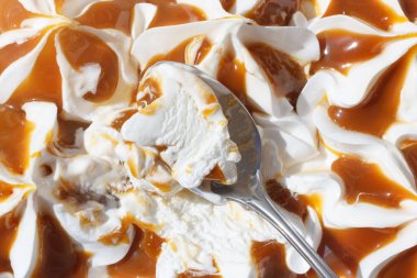 Vanilyalı dondurmayı karamel ile tatmak. Metalik kaşık ve soğuk tatlı. Yukarıdan yakın görünüm.