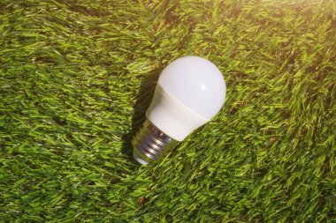 Yeşil çimen arka planında modern lamba. Enerji ekonomisi ve çevre dostu ev teknolojileri kavramı.