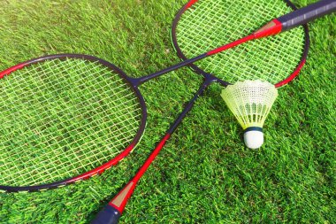 The badminton kit with two rockets and plastic shuttlecock on the grass. Sport items for outdoor activity, closeup view