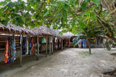 Malı ve turistleri Vanuatu 'daki Mystery Island' dan alışveriş yapan sazdan çatı sığınağı altındaki pazar