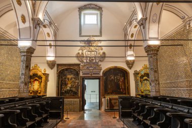 Yüksek Koro Odası 'nın ana manzarasında ön duvarda resimler ve yan duvarlarda dekoratif fayanslar var..