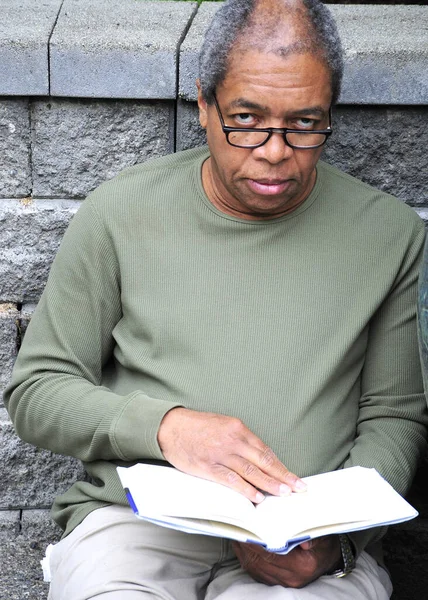 African American Male Senior Reading Book Outdoors — Stock Photo, Image